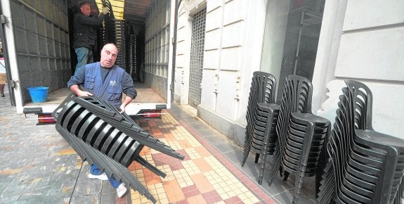 Dos operarios de Sillas Gil descargan un camión, en la calle del Carmen, la víspera del Viernes de Dolores. 