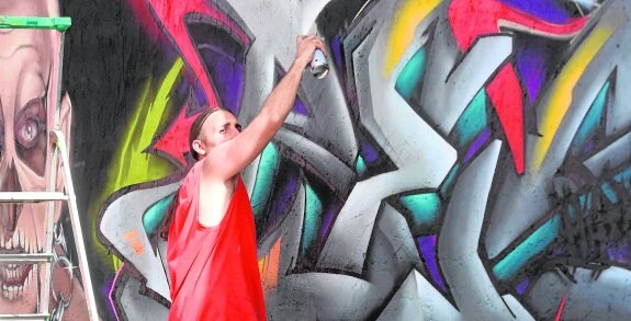 Un grafitero se afana en acabar su obra, una de las que cubrieron ayer un muro de cincuenta metros en el barrio de San Pío.