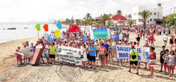 Los manifestantes con pancartas, en el momento que se acercaron a la playa para escenificar el estado del Mar Menor. 