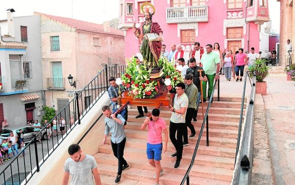 Los jóvenes anderos bajan las escaleras de la parroquia con el trono de San Bartolomé. 