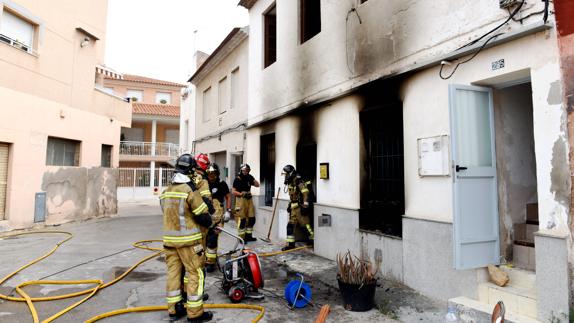 Los bomberos trabajan en la casa quemada. 