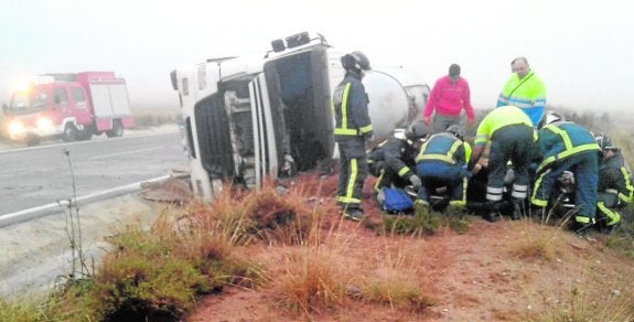 Sanitarios y bomberos atienden al camionero herido tras ser rescatado del interior del tráiler. 