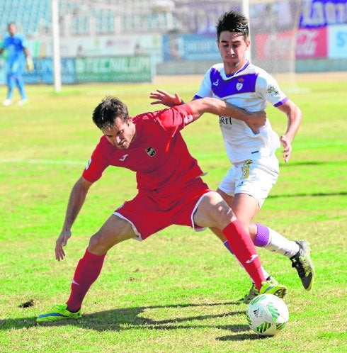 Pina, capitán del Lorca, forcejea con un rival por controlar el balón.