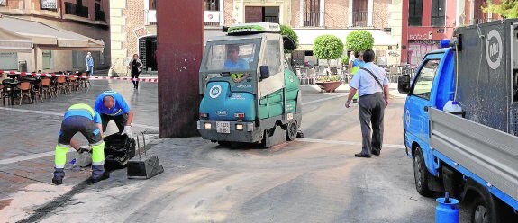 Operarios municipales afanándose ayer en limpiar la mancha de aceite en el suelo de la Plaza Romea, en Murcia. 