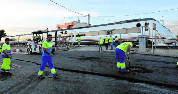 Operarios trabajando ayer en la renovación del pavimento en el paso a nivel de Senda de los Garres. :: GUILLERMO CARRIÓN / AGM