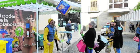 Un monitor lanza un dado en la carpa instalada ayer, en la Plaza de Belluga, para que una señora responda a las preguntas sobre reciclaje. 