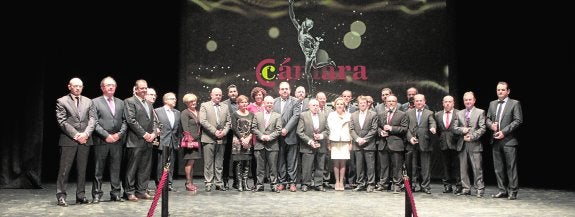 Tradicional foto de familia de los premiados, autoridades y representantes de la Cámara de Comercio de Lorca sobre el escenario del Teatro Guerra. 