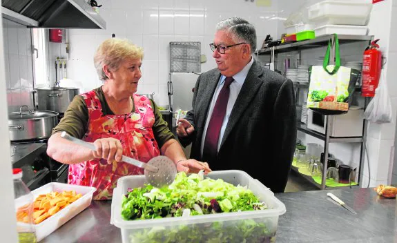 La cocinera de la Hospitalidad Caridad Fernández prepara una ensalada, junto al presidente de la institución, Vicente Villar.