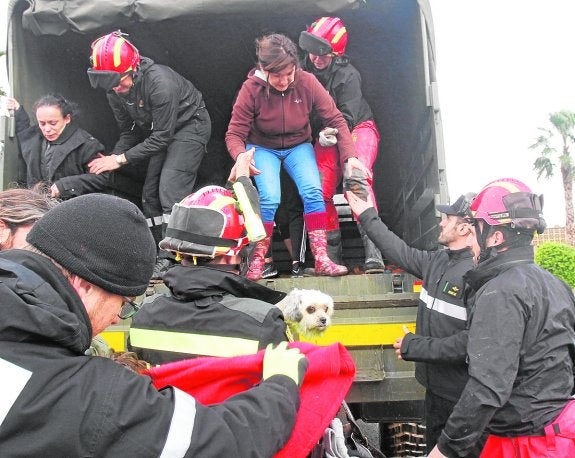 Miembros de la UME bajan de un camión a dos mujeres a las que rescataron.