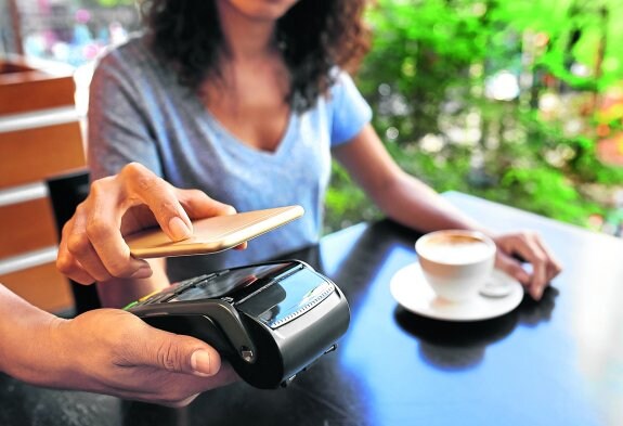 Una mujer usa su teléfono móvil para pagar la comida en un restaurante. 