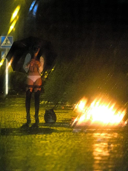 Una prostituta se calienta junto a una hoguera apostada en una esquina del polígono Marconi, en la zona sur de Madrid, a la espera de clientes.