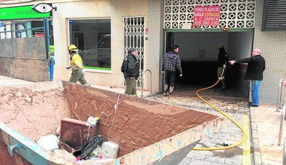 Varias personas realizan labores de limpieza en uno de los garajes afectados en Los Alcázares. 