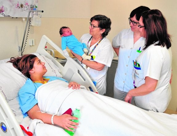 Saray Amador Fernández observa a su hijo Juan, en brazos de la enfermera Concha Jiménez. A su lado, Esmeralda Miras y Milagros García, también enfermeras.