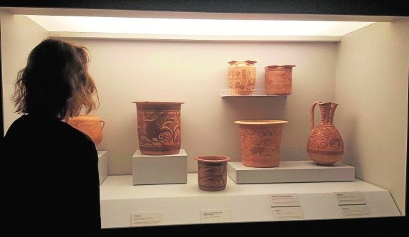 Una mujer observa vasijas y urnas en una de las vitrinas del Museo Arqueológico de Murcia. 