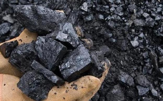 Un minero cogiendo carbón sobre su mano.