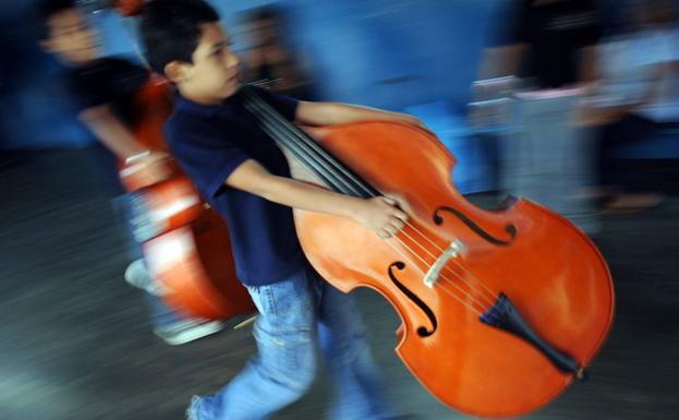 Varios niños trasladan instrumentos musicales. 