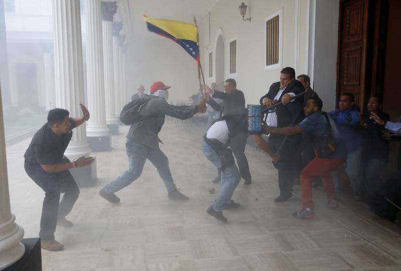 Decenas de personas, algunas encapuchadas, con palos y tubos, y vestidas de rojo, entraron a los jardines de la Asamblea Nacional y detonaron cohetes de fuegos artificiales, desatando el caos