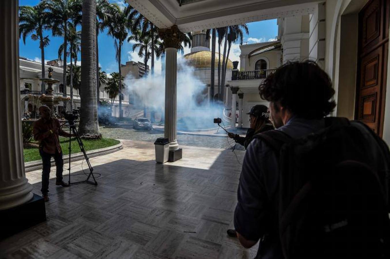 Decenas de personas, algunas encapuchadas, con palos y tubos, y vestidas de rojo, entraron a los jardines de la Asamblea Nacional y detonaron cohetes de fuegos artificiales, desatando el caos