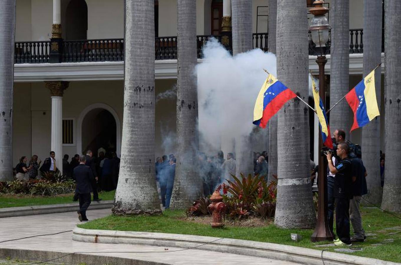 Decenas de personas, algunas encapuchadas, con palos y tubos, y vestidas de rojo, entraron a los jardines de la Asamblea Nacional y detonaron cohetes de fuegos artificiales, desatando el caos