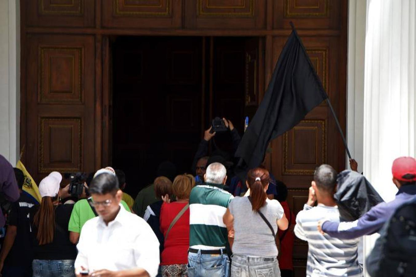 Decenas de personas, algunas encapuchadas, con palos y tubos, y vestidas de rojo, entraron a los jardines de la Asamblea Nacional y detonaron cohetes de fuegos artificiales, desatando el caos