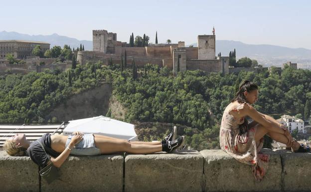 Unos turistas descansan y toman el sol en Granada. 