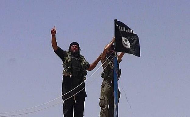 Miembros del Daesh colocan una bandera yihadista.