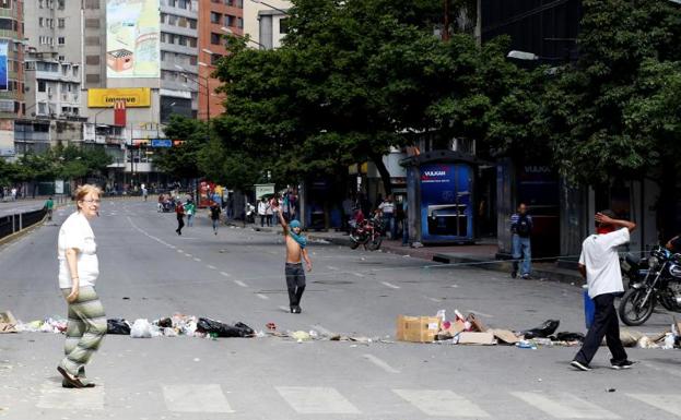 Varias personas caminan por una calle de Caracas vacía.