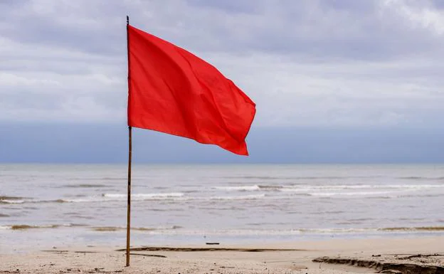 Imagen de una bandera roja en una playa.