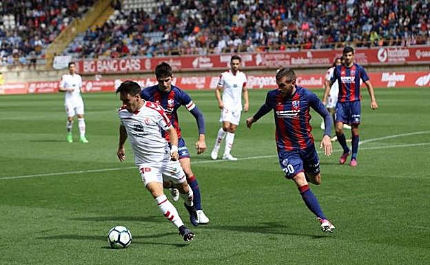 Iza controla el balón ante dos jugadores del Huesca.