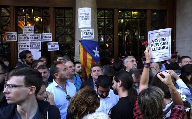 Imagen principal - Varios mossos y manifestantes tras los registros.