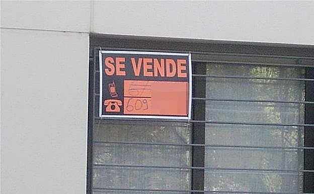 Imagen de un piso con un cartel para su venta.