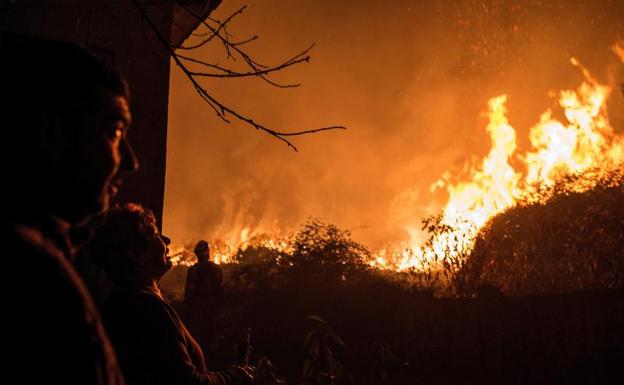 Varias personas observan uno de los incendios en Galicia. 