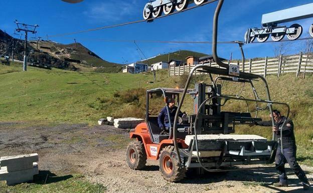 Dos operarios realizan, cumpliendo la normativa, comprobaciones de carga en el telesilla del Brañillín. 