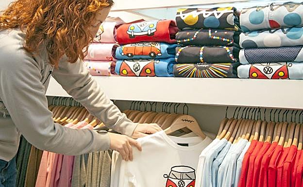 Una dependienta muestra camisetas en un comercio textil.