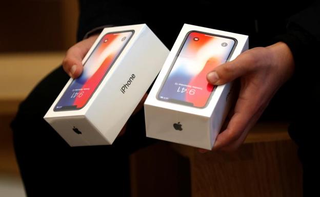 Un hombre sostiene dos cajas con el nuevo iPhone X.