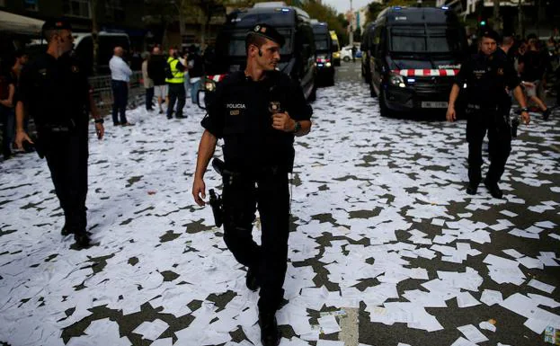 Mossos d´Esquadra andado por una calle cubierta de papeletas del referendum del 1-O. 