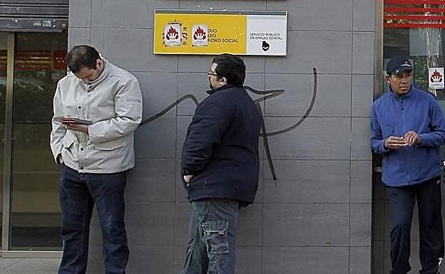 VArios trabajadores esperan ante una oficina de empleo.
