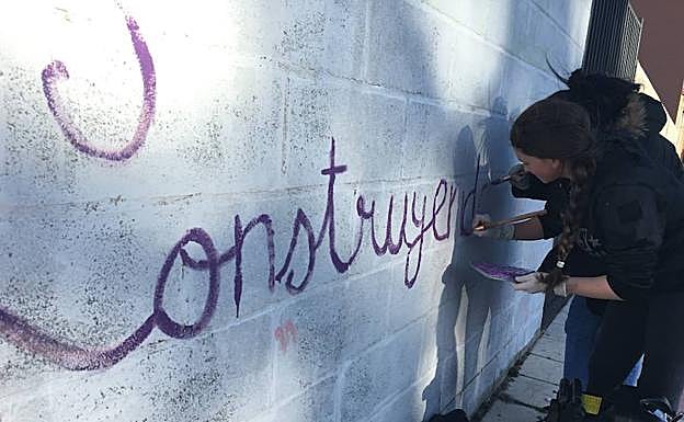 Una mujer pintando el mural. 