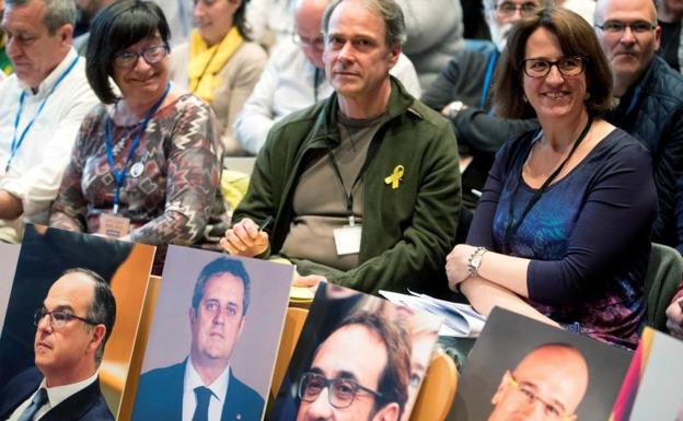 Miembros de la ANC sostienen imágenes de dirigentes políticos catalanes.