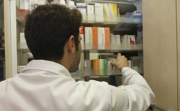 Un farmacéutico busca un medicamento en un estante de su botica. 