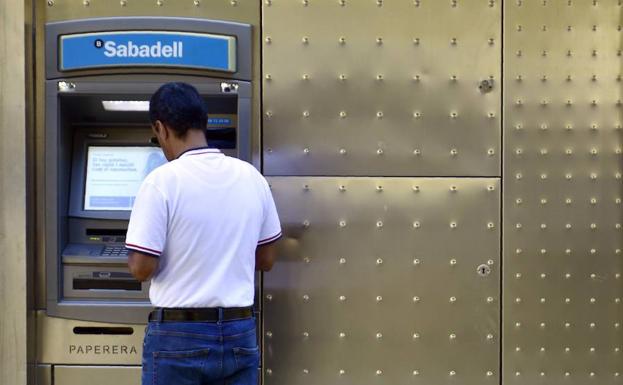 Un hombre usa un cajero automático de Banco Sabadell. 