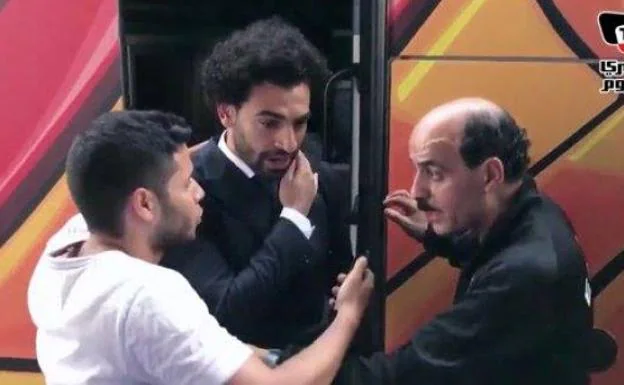 Un escolta aparta a un hincha para que no toque el hombro de Salah.