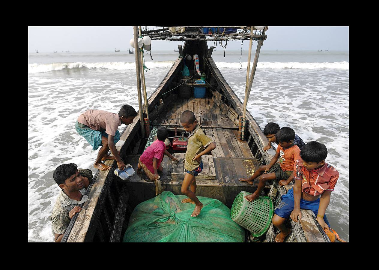 Una parte de los refugiados Rohingya que huyeron de Myanmar han encontrado trabajo en las pesquerías de la vecina Bangladesh. El campamento de refugiados de Shamlapur, cercano a una colonia de pescadores, es el hogar de unos 10.000 refugiados, que trabajan en la mar por alrededor de 3 dólares y una parte de las capturas. Las mujeres acompañan a sus maridos en la tarea secando y clasificando los peces sobre enormes mesas de madera, envueltas en moscas por un salario aún menor. Según funcionarios del Gobierno esta industria genera ingresos de 20 millones de dólares. Pero incluso los niños tienen que trabajar duro.
