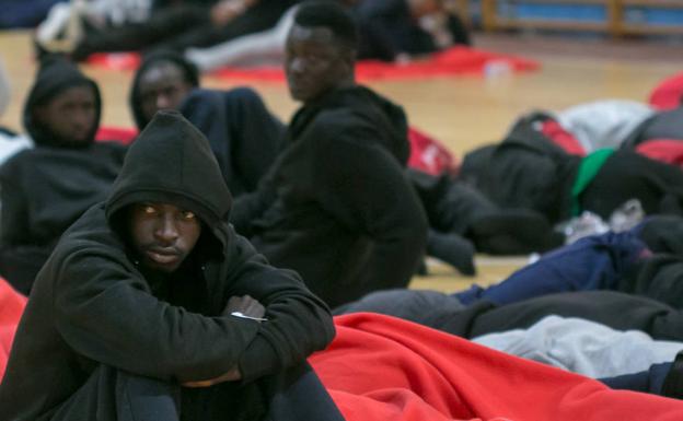 Varios migrantes en un polideportivo. 