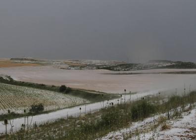 Imagen secundaria 1 - A la izquierda, una tormenta inesperada en Valladolid. Arriba, a la derecha, una tormenta de granizo en la zona de Herrera de Pisuerga que anegó tierras de cultivo. Debajo, la carretera A-67 colapsada por las fuertes lluvias. 