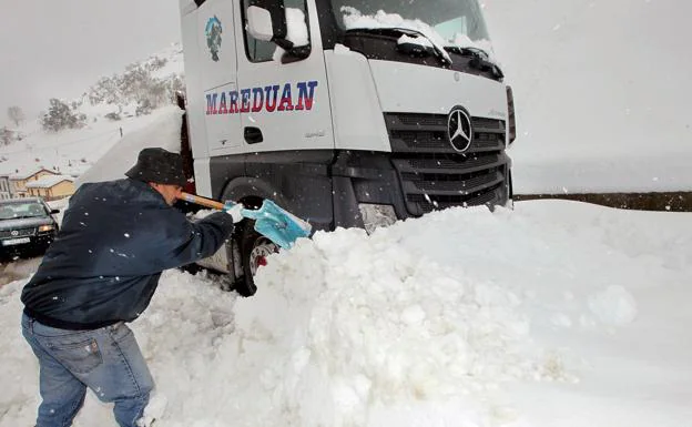 Un conductor intenta liberar su camión entre la nieve.