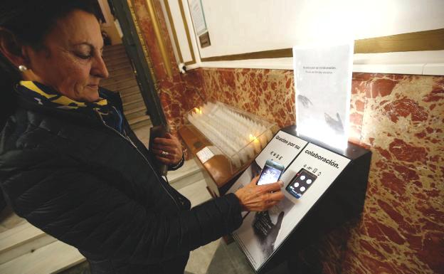 Una mujer usa su teléfono móvil para efectuar una donación.