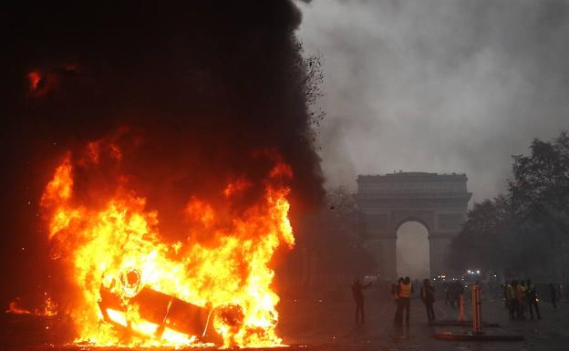 Un coche volcado arde en los Campos Elíseos, durante la jornada de protesta de los 'chalecos amarillos' contra las políticas de Macron.