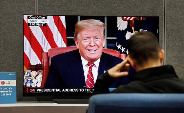 Un hombre ve por televisión el discurso de Trump desde el Despacho Oval.