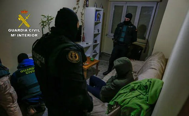 La Guardia Civil registra la vivienda del presunto yihadista, sentado en el sofá, en Zaragoza.